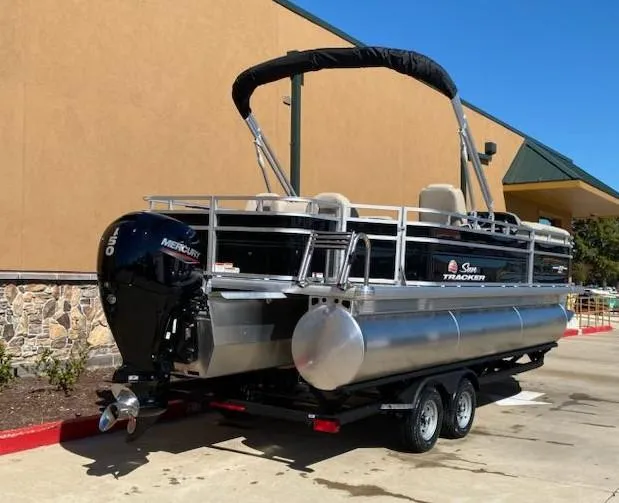Slide: The Image of 2025 Sun Tracker SportFish 22 XP3 pontoon boat on trailer, parked outdoors. - 4