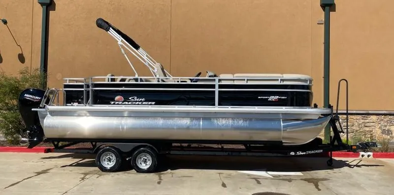 Slide: The Image of 2025 Sun Tracker SportFish 22 XP3 pontoon boat on trailer, parked outdoors. - 6