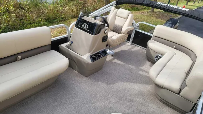 Slide: The Image of 2025 Sun Tracker Party Barge 16 DLX interior with beige seating and steering console. - 3