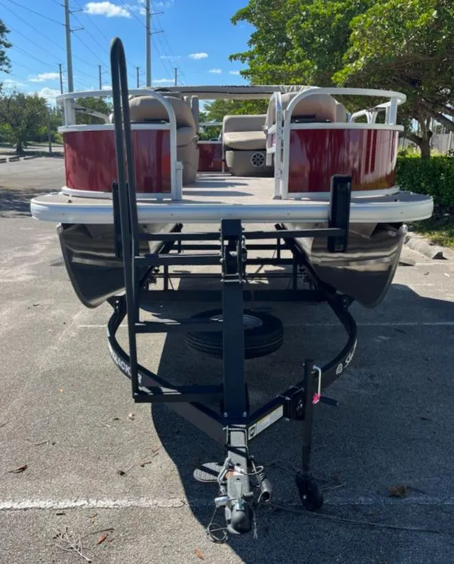 Slide: The Image of 2025 Sun Tracker Bass Buggy 16 XL Select pontoon boat on trailer in parking lot. - 2