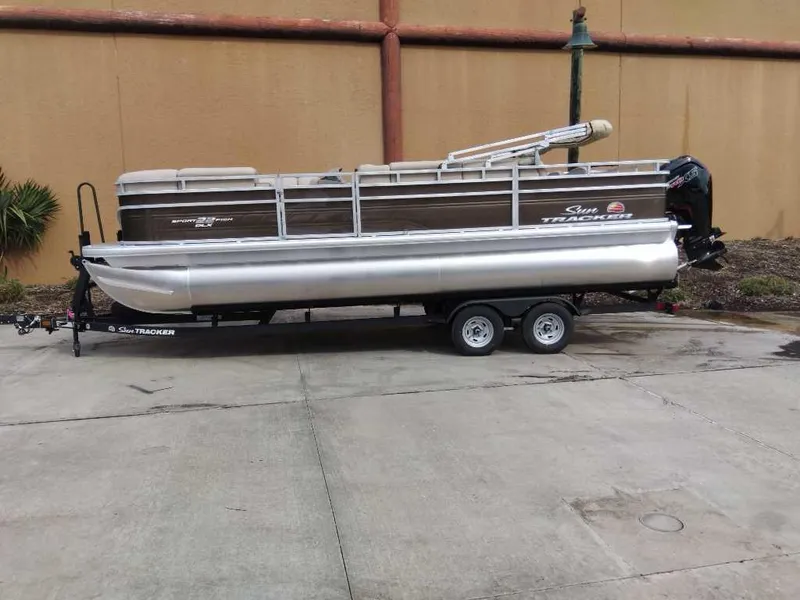 The Image of 2025 Sun Tracker SportFish 22 DLX pontoon boat on trailer, parked outdoors. - 0