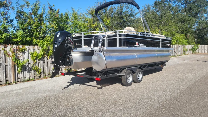 Slide: The Image of 2025 Sun Tracker Sportfish 24 XP3 pontoon boat on trailer, parked outdoors. - 4