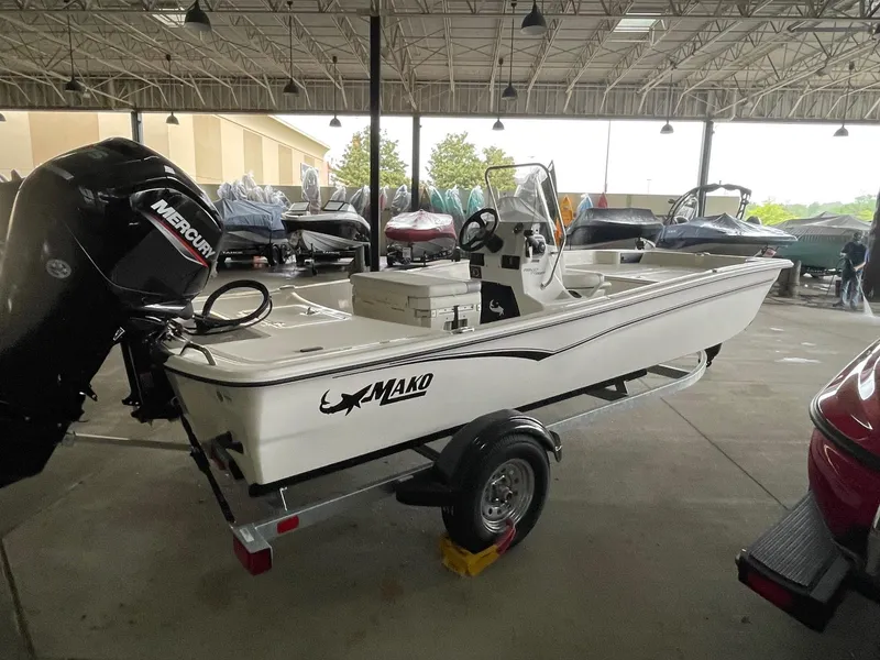 Slide: The Image of 2025 Mako Pro Skiff 17 CC boat in showroom, featuring a Mercury outboard motor. - 2