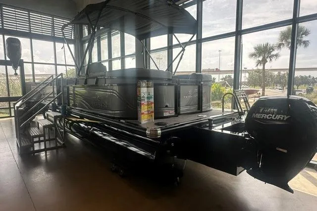 Slide: The Image of 2025 Regency 230 DL3 pontoon boat with Mercury engine displayed indoors. - 1