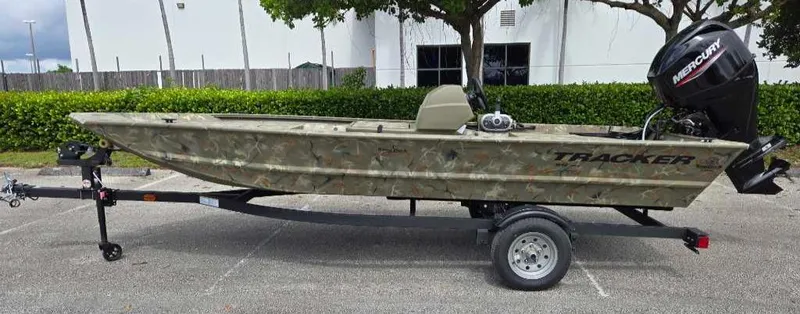 The Image of 2025 Tracker Grizzly 1648 SC boat on trailer, camo design, parked outdoors. - 0
