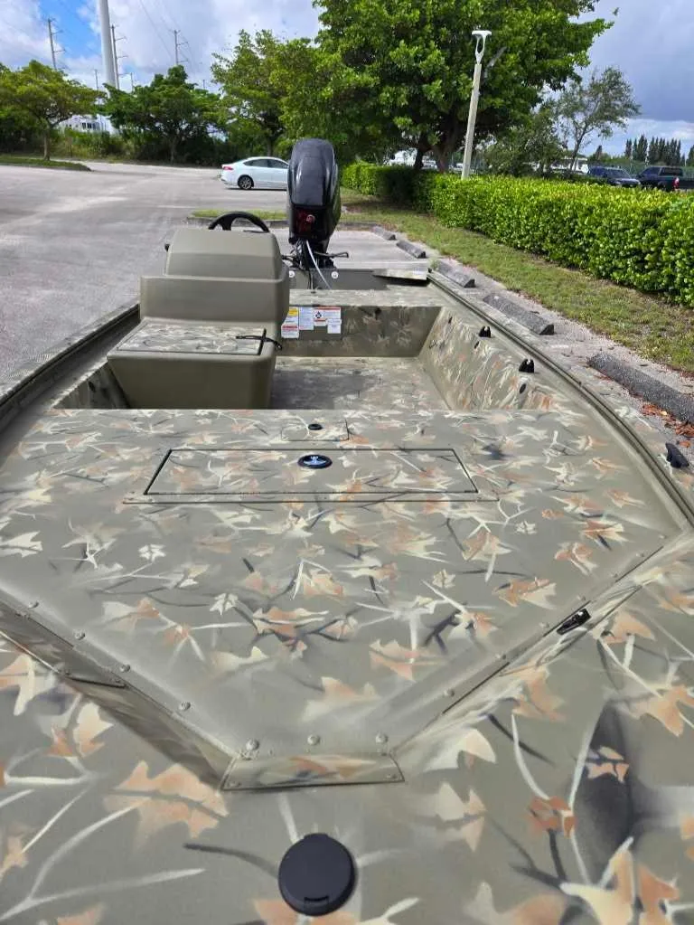 Slide: The Image of 2025 Tracker Grizzly 1648 SC boat with camouflage design in a parking area. - 7