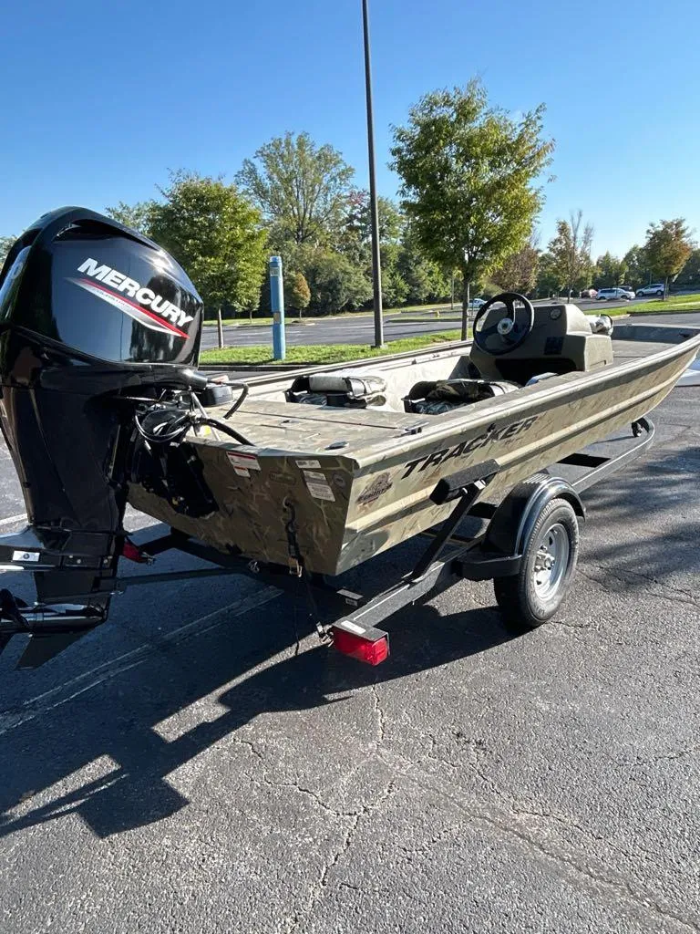 Slide: The Image of 2025 Tracker Grizzly 1754 SC boat with Mercury engine on trailer in parking lot. - 2