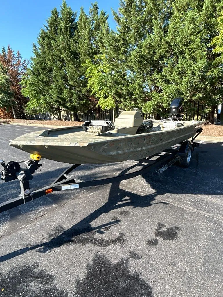 Slide: The Image of 2025 Tracker Grizzly 1754 SC boat on trailer, parked outdoors with trees in background. - 3