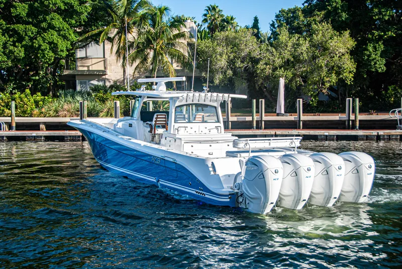 Slide: The Image of 2022 HCB 53 Sueños boat with four engines docked near lush greenery. - 22