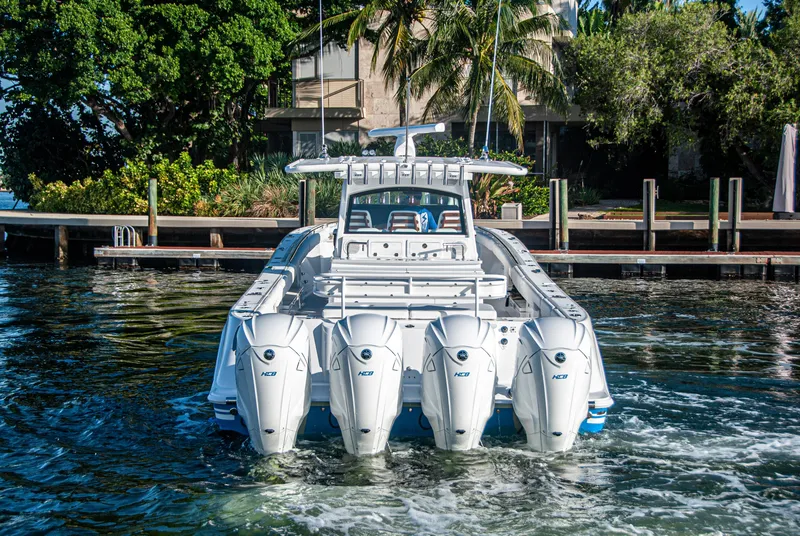 Slide: The Image of 2022 HCB 53 Sueños boat with multiple outboard engines, docked near lush greenery. - 23