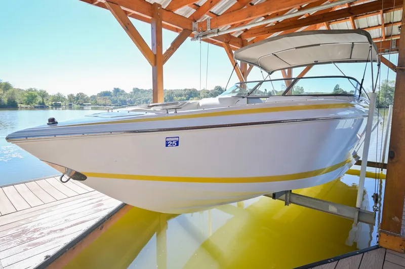 The Image of 2002 Cobalt 262 boat docked under a wooden canopy on a sunny day. - 0