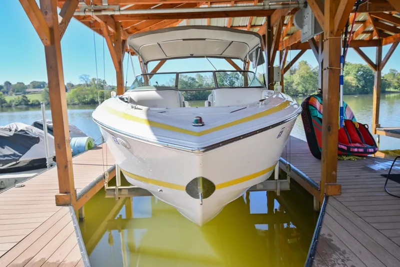Slide: The Image of 2002 Cobalt 262 boat docked under wooden shelter on a sunny day. - 1
