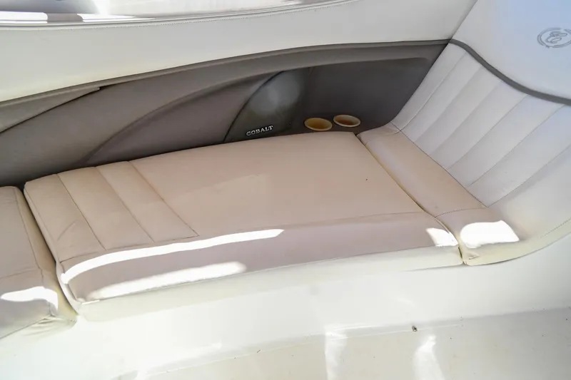 Slide: The Image of 2002 Cobalt 262 boat interior with white cushioned seating and cup holders. - 37