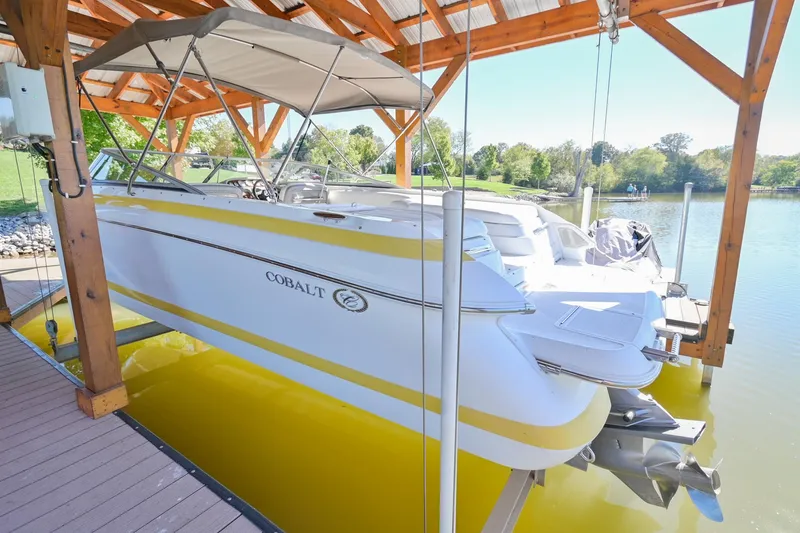 Slide: The Image of 2002 Cobalt 262 boat docked under wooden shelter on a sunny day. - 4