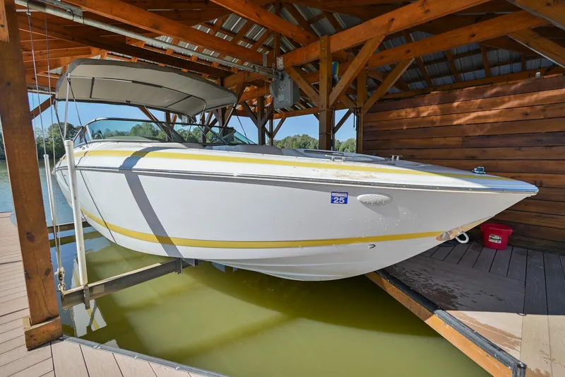 Slide: The Image of 2002 Cobalt 262 boat docked in a wooden boathouse, partially lifted above water. - 5