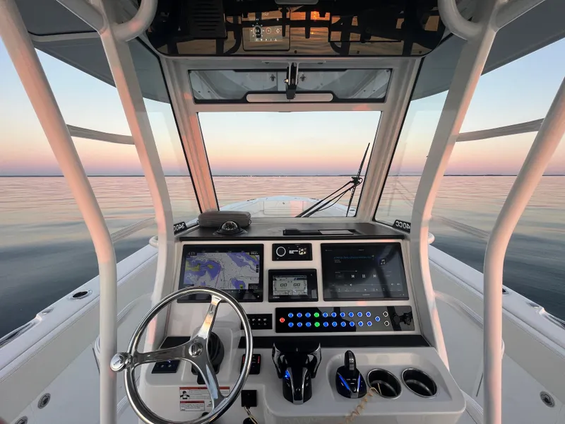 Slide: The Image of Edgewater 340CC 2022 boat cockpit with navigation controls at sunset on calm waters. - 17