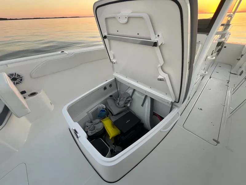 Slide: The Image of Edgewater 340CC 2022 boat storage compartment open at sunset on calm water. - 23
