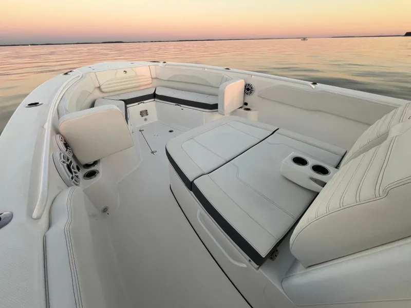 Slide: The Image of 2022 Edgewater 340CC boat interior with white seating at sunset on calm water. - 32