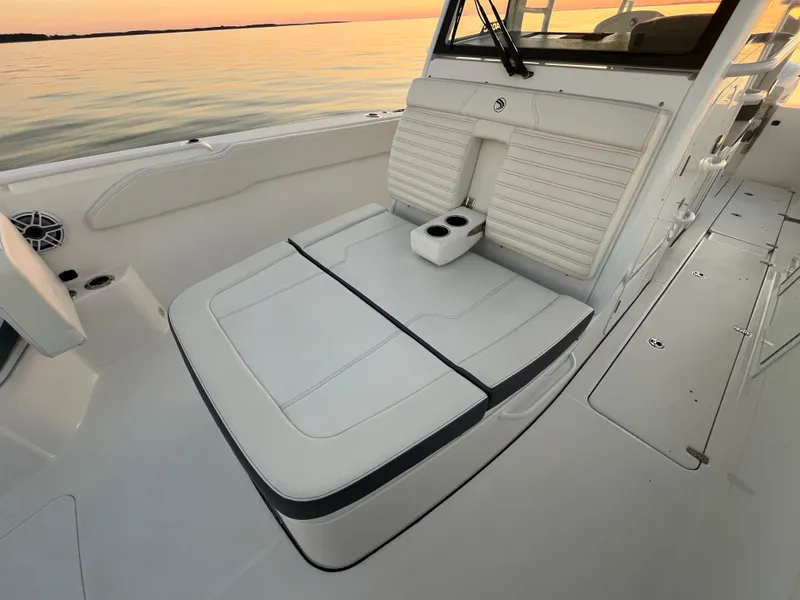 Slide: The Image of Edgewater 340CC 2022 boat interior with white seating and cup holders at sunset. - 33