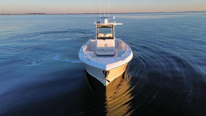 Slide: The Image of 2022 Edgewater 340CC boat cruising on calm water at sunset. - 6