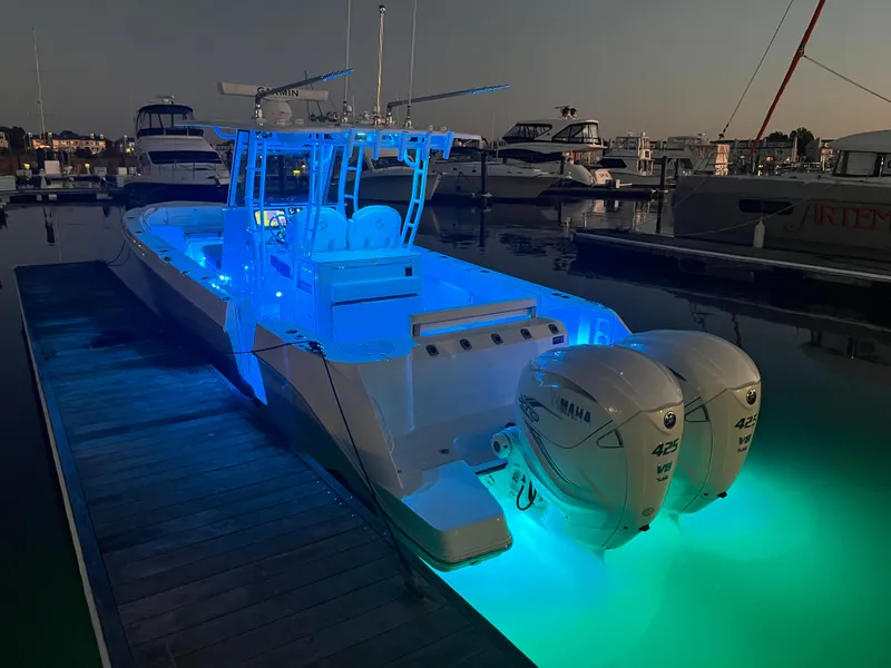 Slide: The Image of 2022 Edgewater 340CC boat with blue LED lights docked at night. - 8