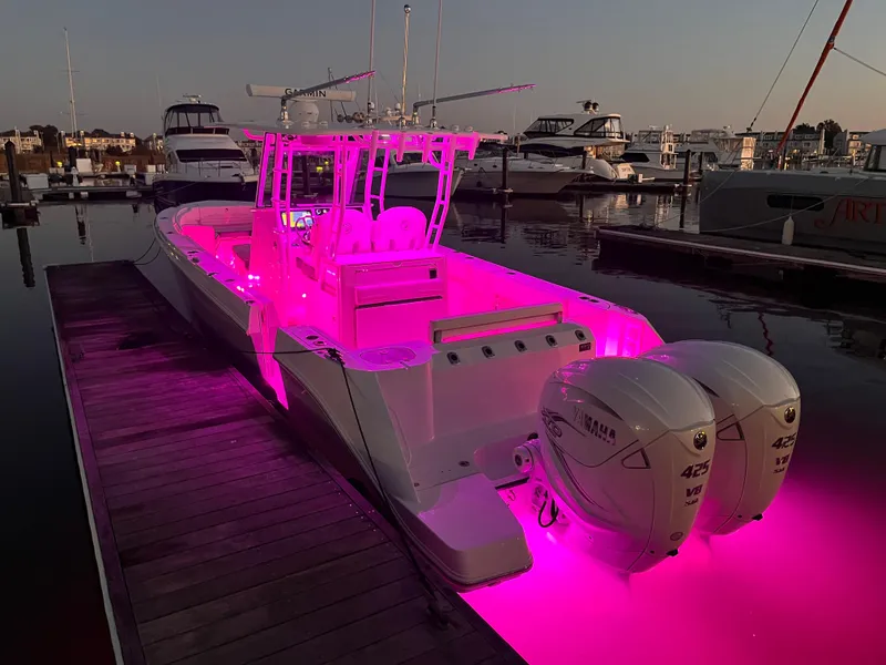 Slide: The Image of Edgewater 340CC 2022 boat with vibrant pink LED lights at marina dock. - 9