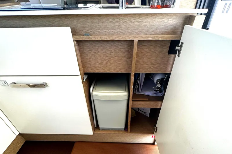 Slide: The Image of Open cabinet on 2019 Prestige 460 Fly Bridge yacht, showing storage and trash bin. - 16