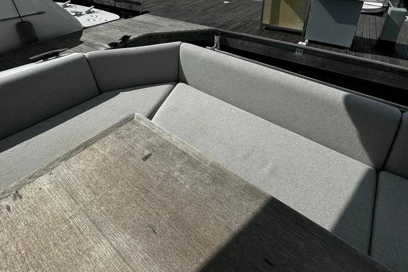 Slide: The Image of Prestige 460 Fly Bridge 2019 yacht seating area with wooden table, docked at marina. - 6