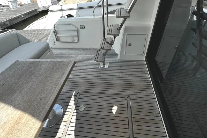 Slide: The Image of Prestige 460 Fly Bridge 2019 yacht deck with wooden flooring and seating area. - 7