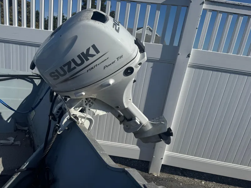 Slide: The Image of 2016 Starcraft SF 14 boat with Suzuki outboard motor, parked near a white fence. - 5