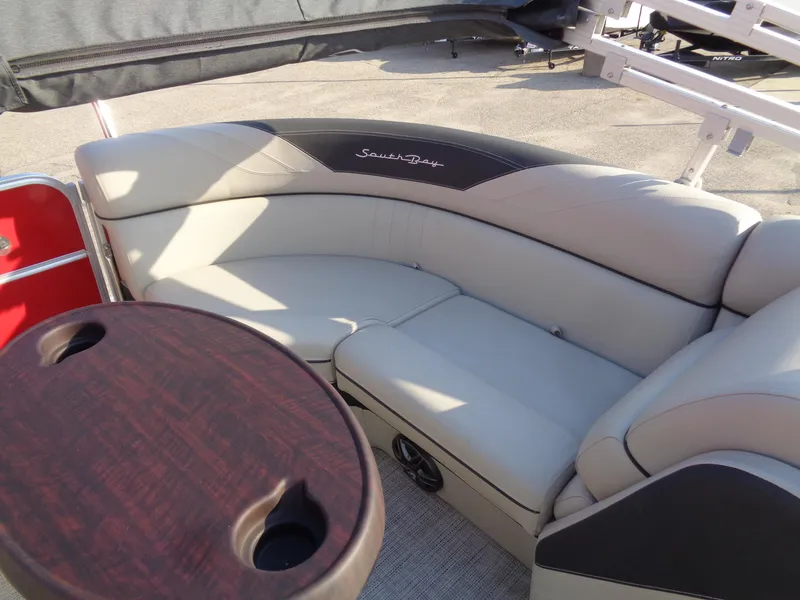 Slide: The Image of 2022 South Bay 222RS pontoon boat interior with plush seating and wooden table. - 13