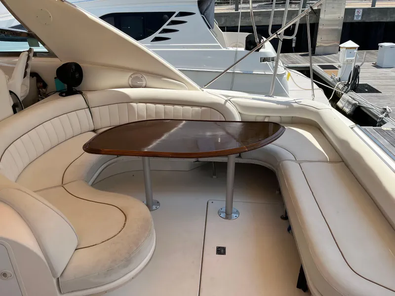 Slide: The Image of 1998 Sea Ray 450 Sundancer yacht with elegant seating and wooden table on deck. - 15