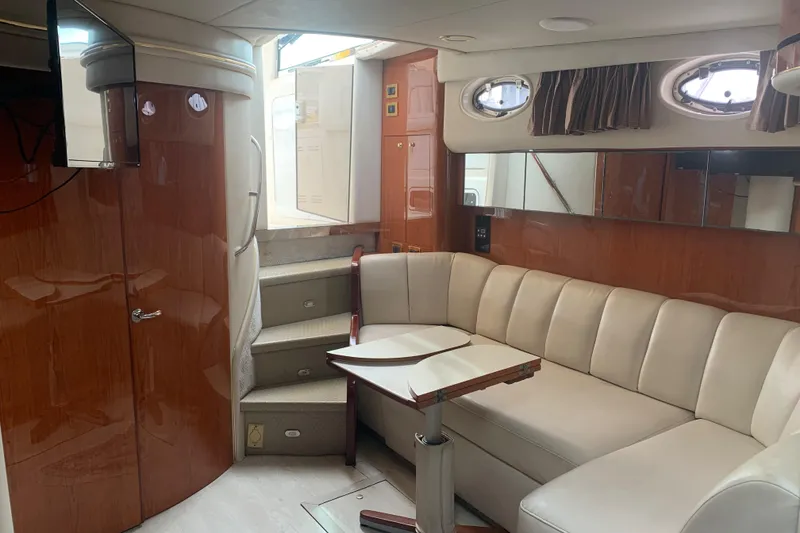Slide: The Image of 1998 Sea Ray 450 Sundancer interior with beige seating, wooden accents, and a compact dining area. - 23