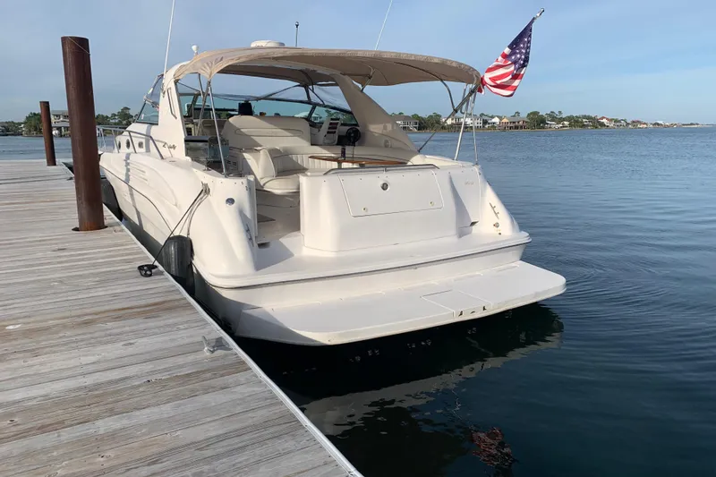 Slide: The Image of 1998 Sea Ray 450 Sundancer yacht docked, featuring a spacious deck and American flag. - 26