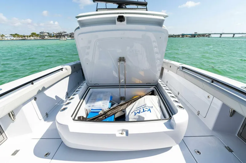 Slide: The Image of 2023 Barker Boatworks 40 High Performance Cat with open storage compartment on turquoise water. - 17