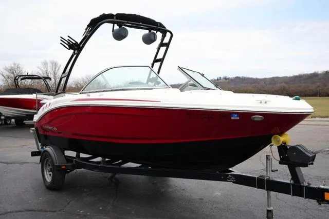 Slide: The Image of 2016 Chaparral H20 19 boat, red and white, on a trailer in a parking lot. - 17