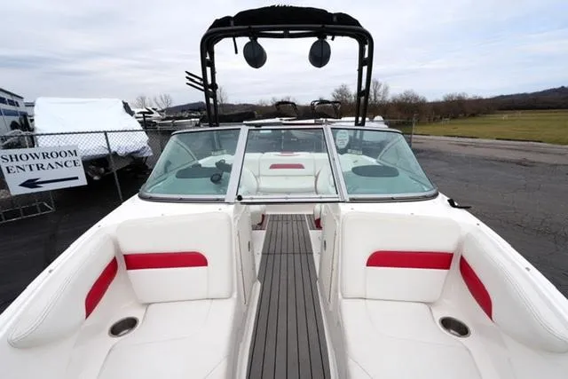Slide: The Image of 2016 Chaparral H20 19 boat interior with red and white seating, docked near showroom. - 25