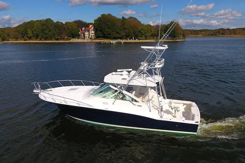 Slide: The Image of 2008 Cabo 40 boat cruising on a scenic lake with a wooded shoreline. - 1