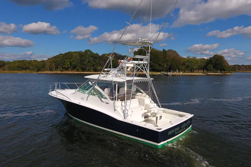 Slide: The Image of 2008 Cabo 40 boat cruising on a scenic lake under a partly cloudy sky. - 2