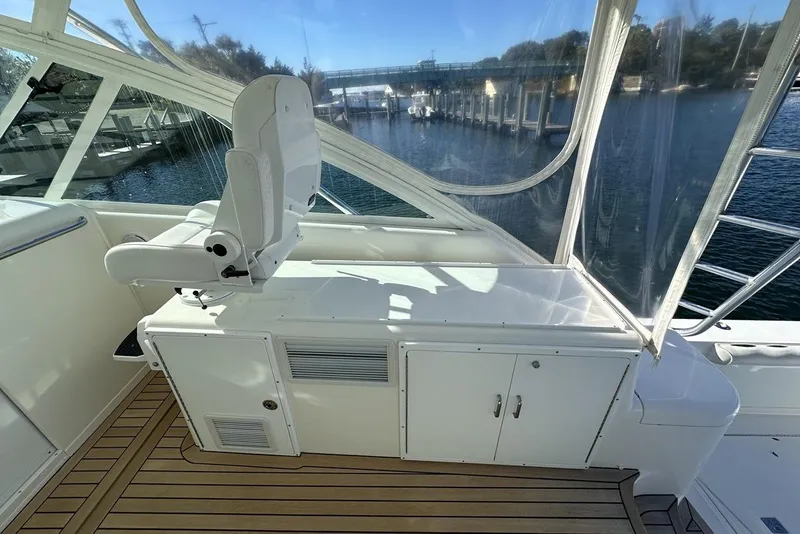 Slide: The Image of 2008 Cabo 40 boat interior with helm seat and wooden deck, overlooking marina. - 24