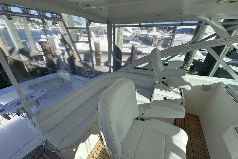 Slide: The Image of 2008 Cabo 40 boat interior with white seating and wooden flooring at a marina. - 26