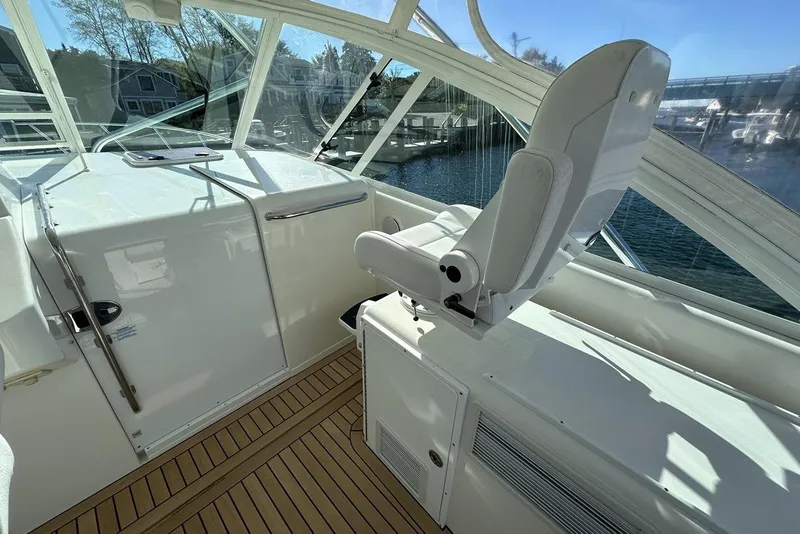 Slide: The Image of 2008 Cabo 40 yacht interior with helm seat and wooden deck, overlooking marina. - 30