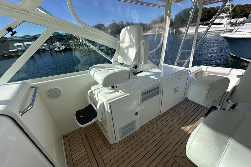 Slide: The Image of 2008 Cabo 40 boat interior with white seating and wooden flooring, docked by the water. - 32