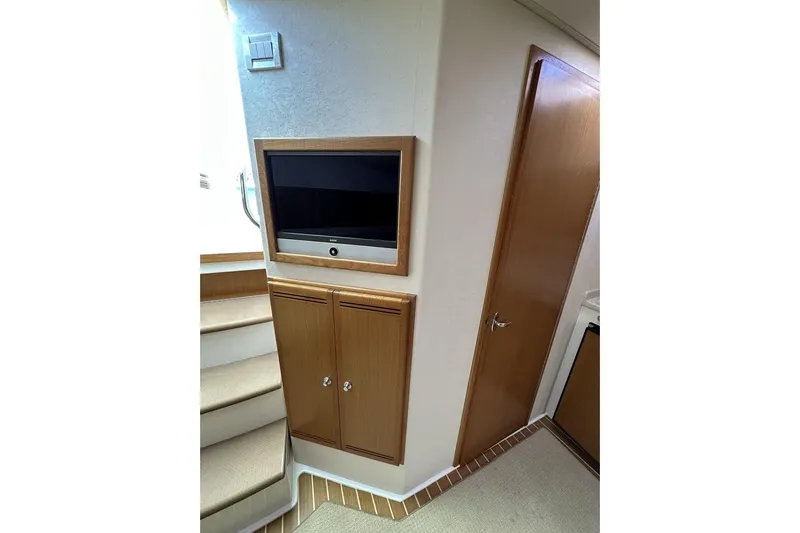 Slide: The Image of Interior of 2008 Cabo 40 yacht with TV, wooden cabinets, and stairs. - 35