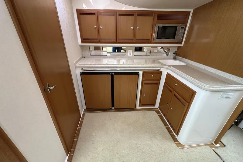 Slide: The Image of Compact kitchen in a 2008 Cabo 40 boat with wooden cabinets and modern appliances. - 40