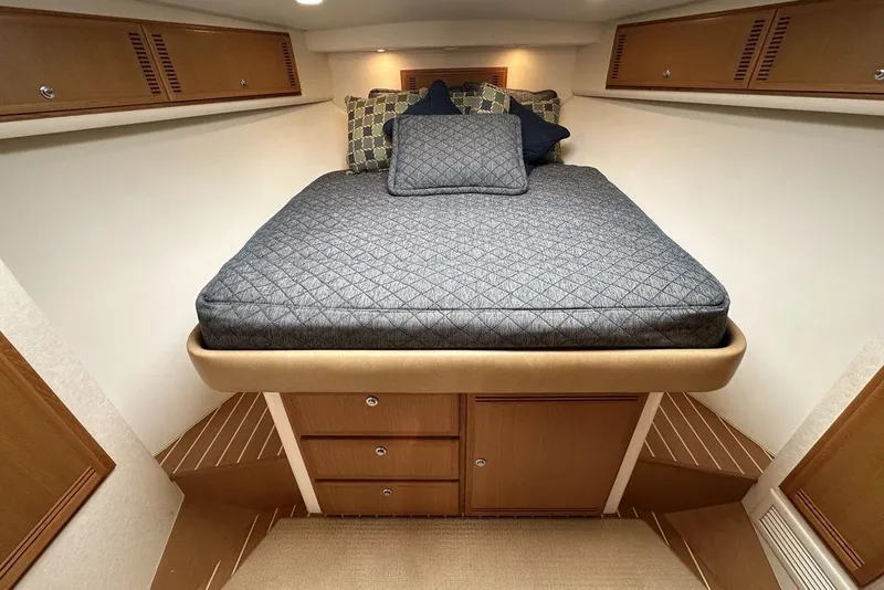 Slide: The Image of 2008 Cabo 40 yacht interior cabin with bed, wooden storage, and overhead cabinets. - 44