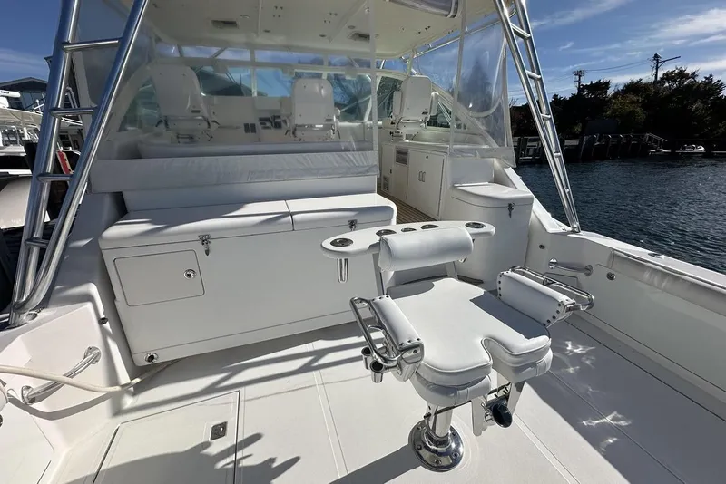 Slide: The Image of 2008 Cabo 40 boat interior with fishing chair and helm, docked by the water. - 57
