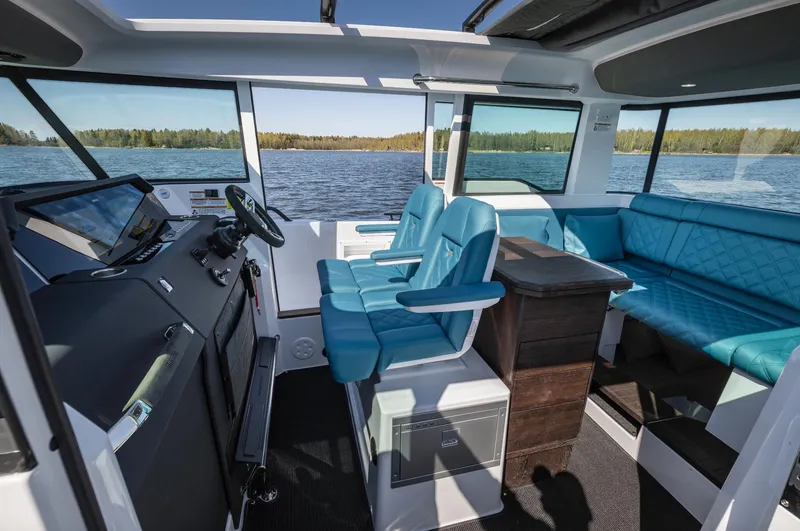 Slide: The Image of 2023 Axopar 37 XC Cross Cabin interior with blue seating and wet bar, on a lake. - 13