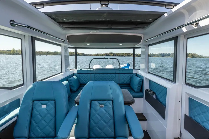 Slide: The Image of 2023 Axopar 37 XC Cross Cabin interior with blue seating and panoramic windows. - 15