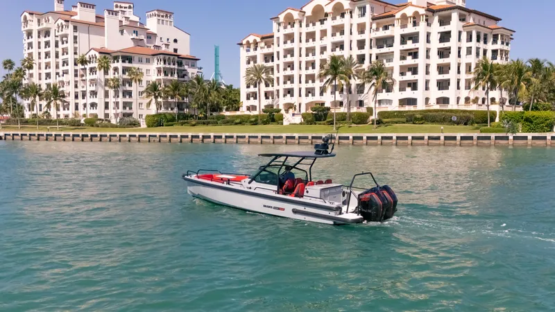 Slide: The Image of 2023 BRABUS Shadow 500 T-Top boat cruising near luxury waterfront apartments. - 7